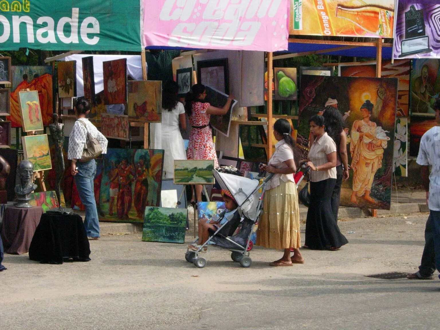 A prominent green banner is displayed over a lively street, with several individuals walking beneath it.