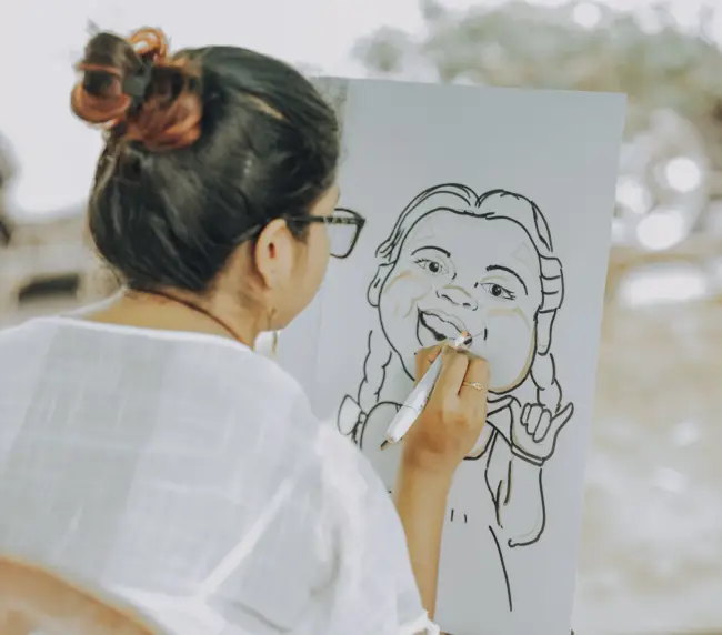 A woman skillfully sketches a caricature of herself, showcasing her artistic talent and creativity.